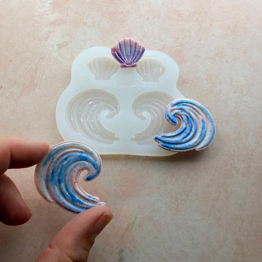Shells and Swells silicone earring mold held in hand showing wave polymer clay piece beside mold with shell and wave cavities