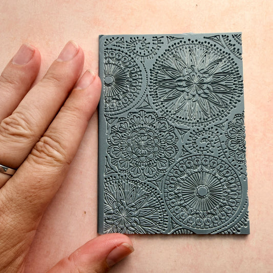 Blooming with Joy rubber stamp for polymer clay held next to hand showing 3x4 inch size with mandala floral detail