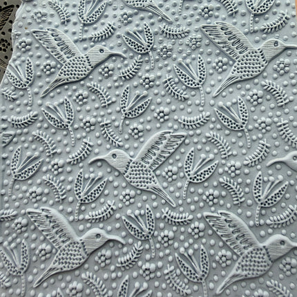 Hummingbird Flight rubber stamp impressed into polymer clay slab showing full all-over hummingbird and floral pattern